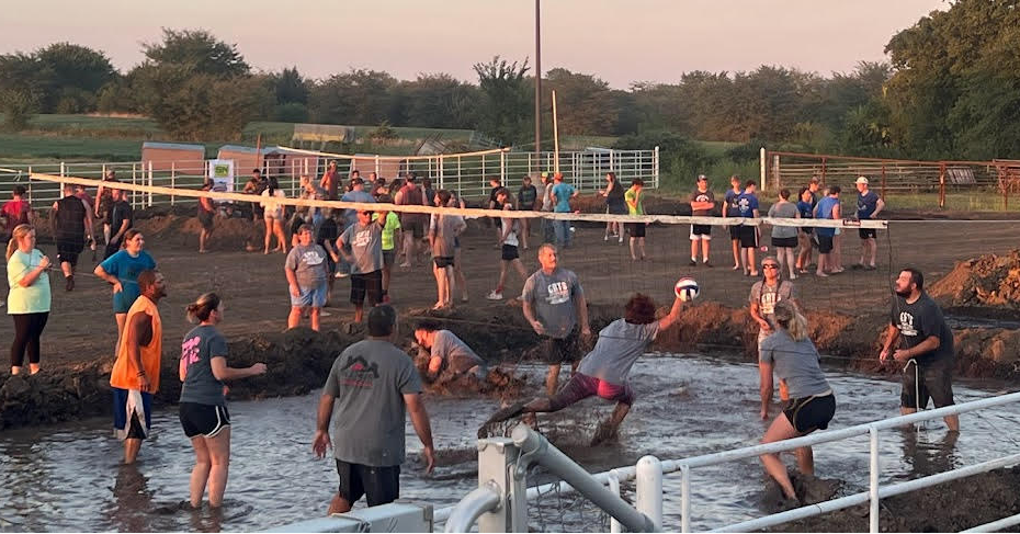People enjoy two teams playing mud volleyball
