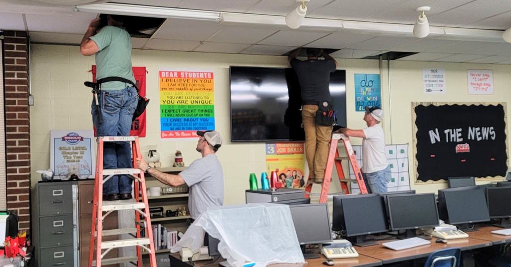 AET students installing the tv in the business classroom